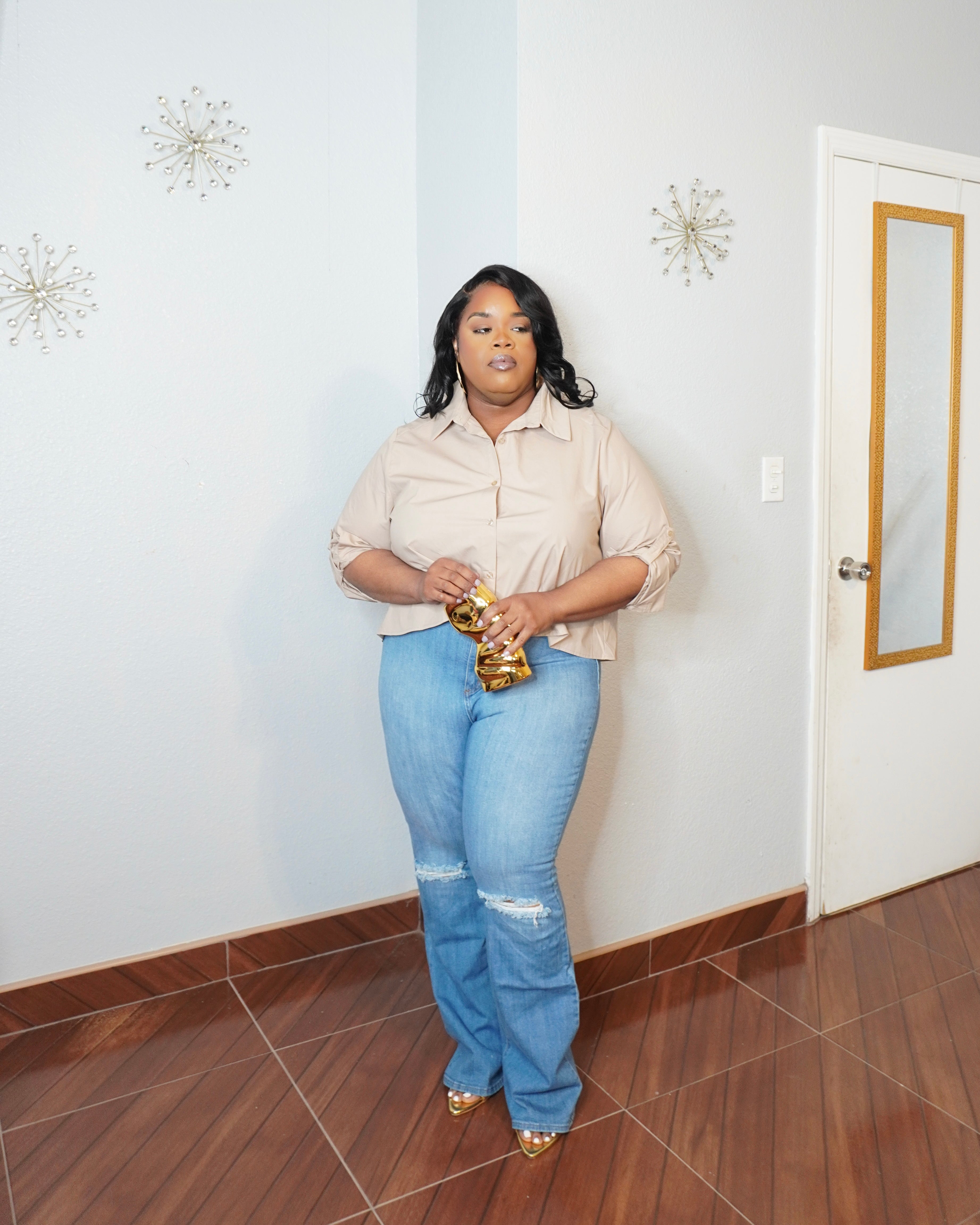 Plus size model wearing blue button down pleated back shirt with denim shorts front view