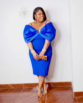 LYSAIRE royal blue plus size off-shoulder midi dress with dramatic draped sleeves, fitted silhouette, gold heels and matching clutch.
