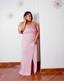 Plus size woman modeling the Rosé Royale pink embellished formal maxi dress by LYSAIRE, highlighting the dramatic thigh-high front slit, flowing dusty pink skirt, sparkling pearl and rhinestone bodice, and curve-enhancing silhouette, perfect for galas, weddings, and elegant evening celebrations.