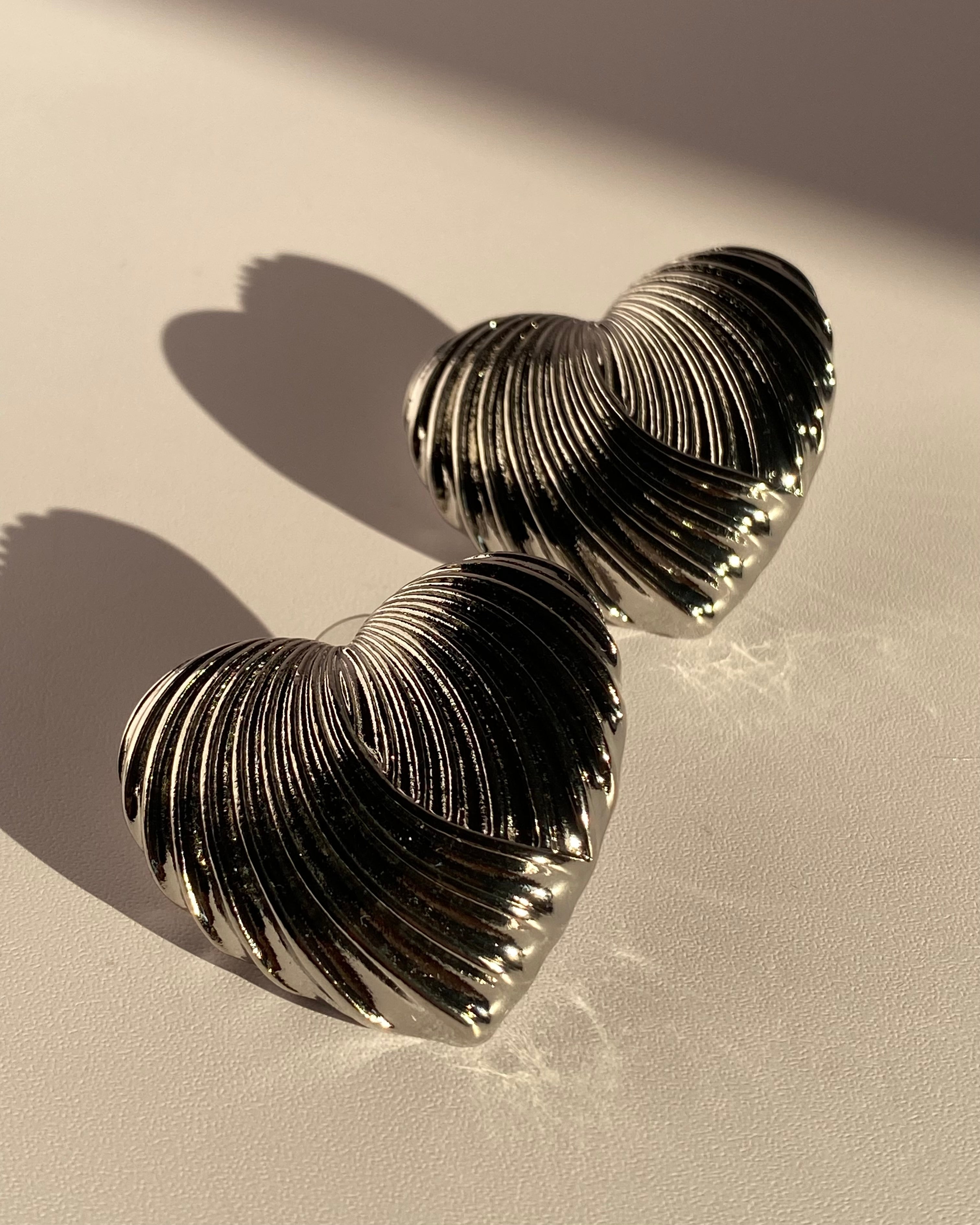 Silver sculpted heart statement earrings with ribbed metallic texture