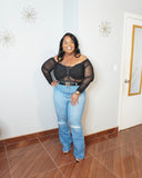 Full body view of plus size woman wearing black mesh top with ripped jeans