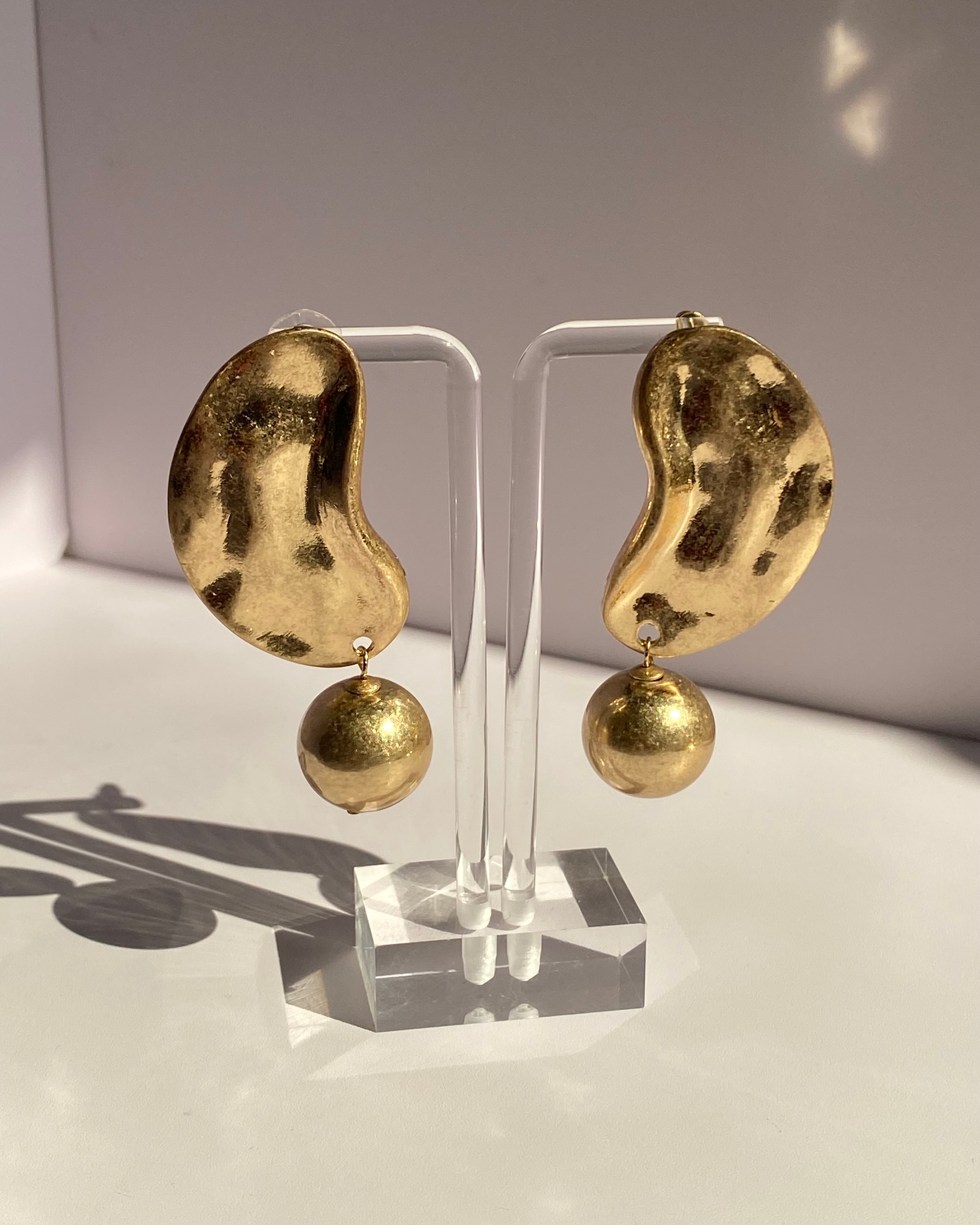 Gold sculpted wave ball drop statement earrings with irregular textured design and dangling gold sphere