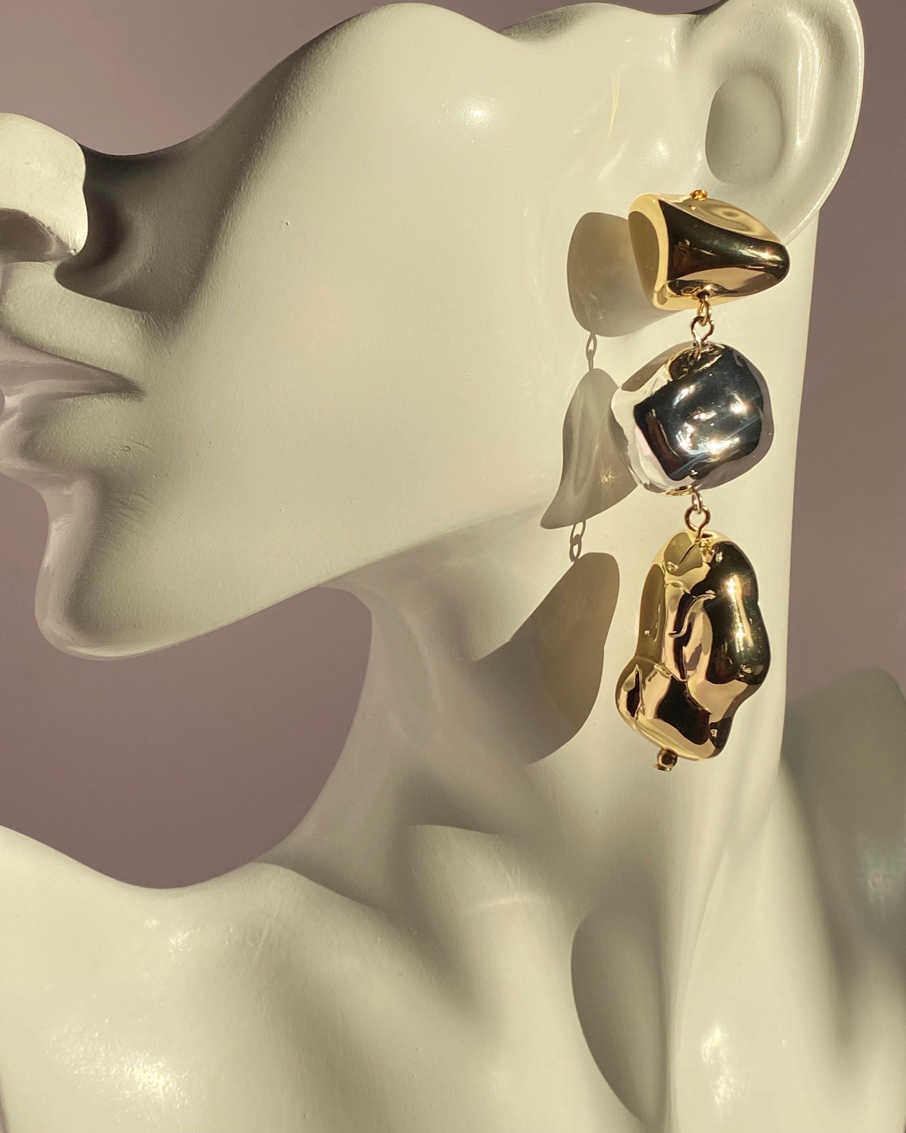 Gold and silver mixed metal abstract drop statement earring displayed on jewelry bust