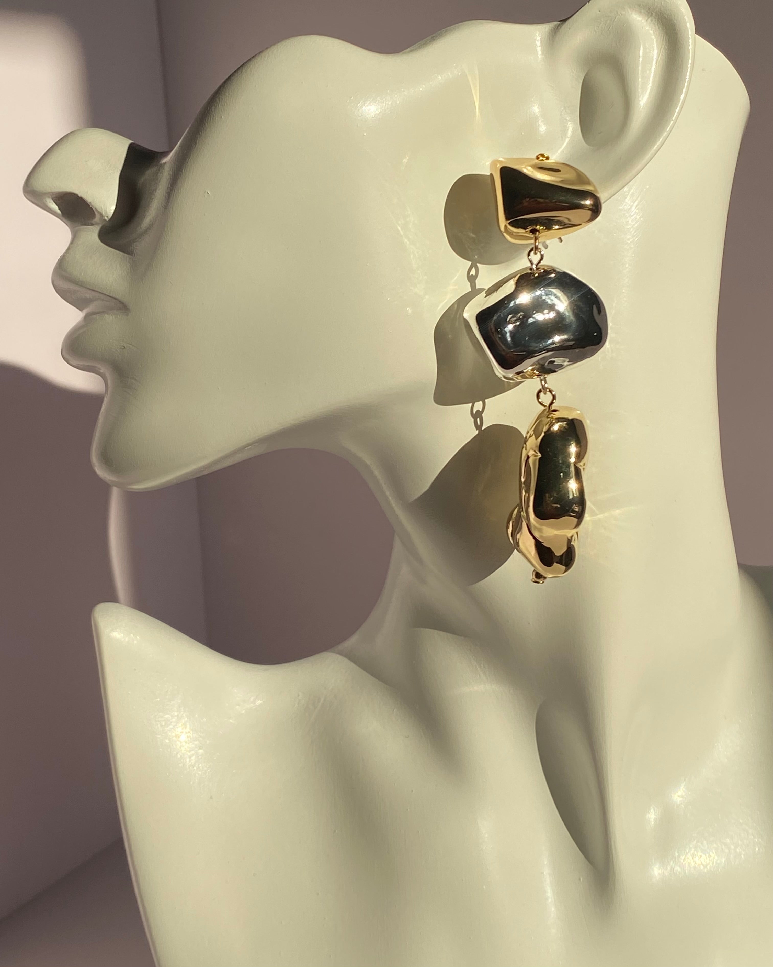 Gold and silver mixed metal abstract drop statement earring displayed on jewelry bust