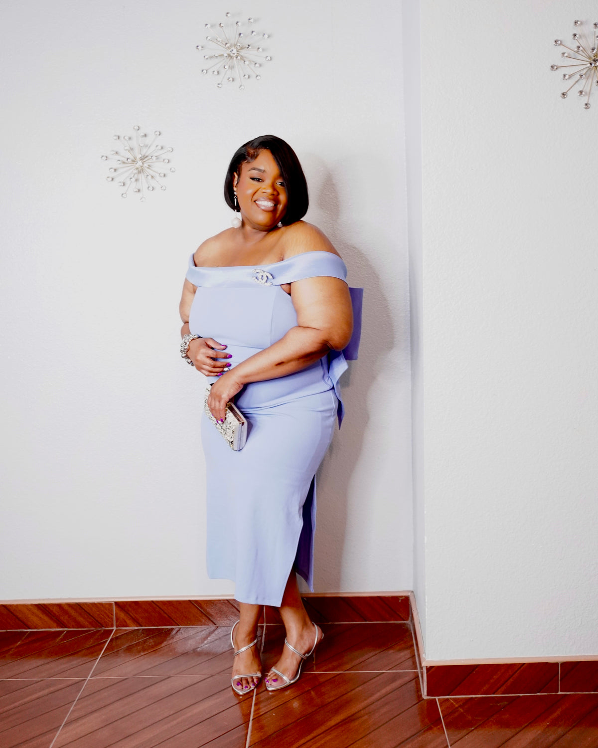 Plus-size woman modeling powder blue statement dress with silver accessories for a formal occasion.